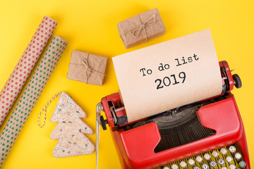 Holidays concept - red typewriter with text "To do list 2019", gift boxes and wrapping paper