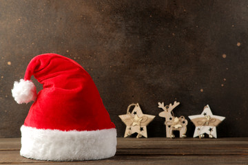 Red Santa Claus hat and garland and New Year's decor on a dark brown background. with space for text. Christmas. new Year.