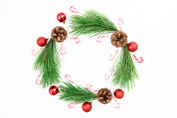 Christmas frame of pine branches and red balls decoration with candy cane on white background. Winter festive background. Flat lay, top view