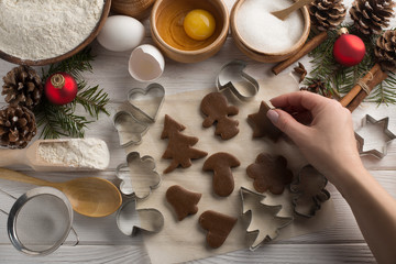 Girl's hands cook holiday Christmas biscuits with decorative molds on a wooden white background. Top view.