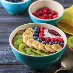 Healthy breakfast with delicious acai smoothie in bowl on dark background
