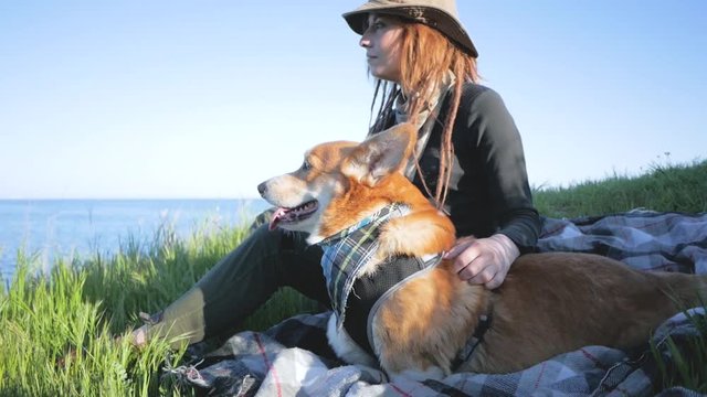 Young female traveler, hiking with corgi dog in mountains