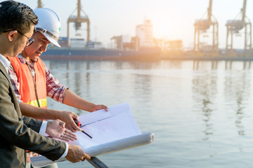 Civil engineer checking  drawing with walkie-talkie with management team at the construction site in port