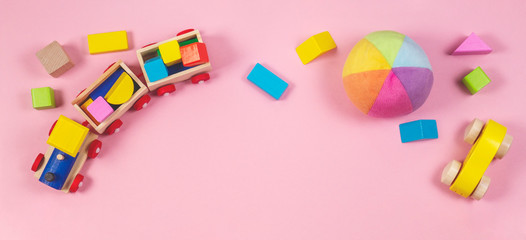 Toys background. Baby kids toys frame with toy cars, colorful wooden cubes on pink background