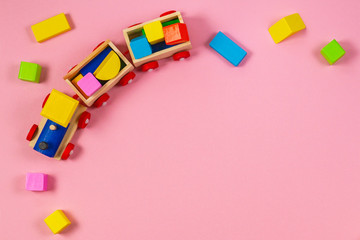 Toys background frame. Wooden toy train with colorful blocks on pastel pink background