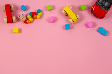 Toys background. Baby kids toys frame with toy cars, colorful wooden cubes on pink background