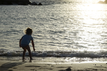 Silhouette of a child running and play on the beach at sunset. Family vacation.
