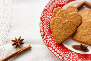 Gingerbread heart-shaped cookies with cinnamon sticks and anise stars on a red plate