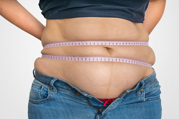 Overweight woman with tape is measuring fat on belly