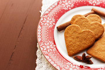 Gingerbread heart-shaped cookies with cinnamon sticks and anise stars on a red plate