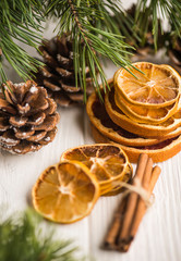 Christmas creative composition with handcraft dry citrus slices, cones, cinnamon sticks on a wooden white background.