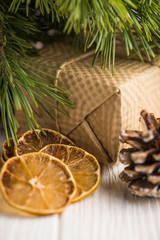 Creative holiday composition with present box, dry citrus slices, green fir branch on a wooden white background.