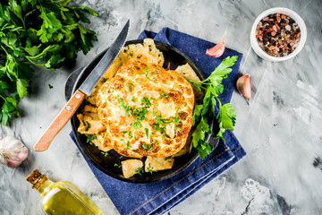 Homemade Whole Roasted Cauliflower in a Skillet, with olive oil and herbs. grey stone or marble background copy space