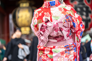 Naklejka premium Young girl wearing Japanese kimono standing in front of Sensoji Temple in Tokyo, Japan. Kimono is a Japanese traditional garment. The word 