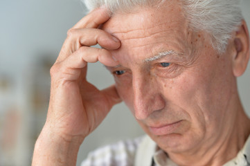 Portrait of senior man with headache holding hands on head