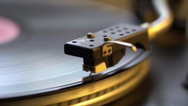 The vinyl record on DJ turntable record player close up. The rotating plate and stylus with the needle close-up