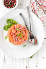 Salmon tartare with red onion, avocado, arugula, bread toast. Beautiful snack, dietary food, appetizer for Christmas holiday. On white wooden background