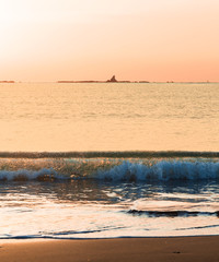 江の島と烏帽子岩の間の水平線に昇る朝陽に照らされたサザンビーチ