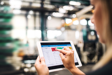 An industrial woman engineer in a factory using tablet.