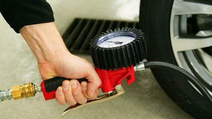 A professional worker in a service station checks (pumps) the pressure of the wheels of a car. Concepts from: Car, Pressure Sensor, Tech Service.