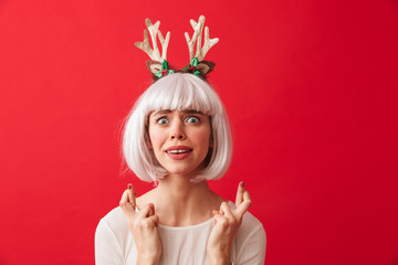 Cute emotional woman isolated over red wall background wearing deer ears costume carnival showing hopeful gesture.