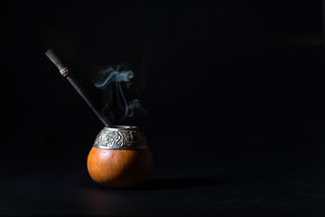 Yerba hot tea mate drink with smoke on black background