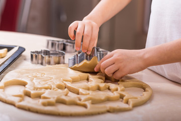 Preparing for the New Year: making cookies with the help of molds in the form of a Christmas tree. Children's hands in the frame. View from above.