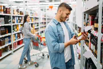 Couple in supermarket, alcohol drinks department