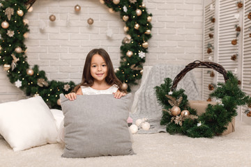 happy girl on the background of the Christmas wreath at home.