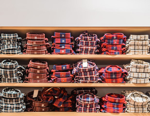 Clothes displayed in store. Copy spase for text. A lot of warm plaid shirts of different color are neatly stacked in a row on the store shelves. Shirts with checkered pattern on a shelves background