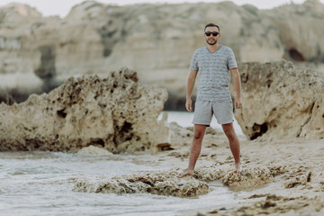 Rocky sea shore with waves. Lonely man is walking along cliff beach