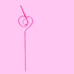 pink straw in the shape of a heart for a cocktail isolated on a pink background