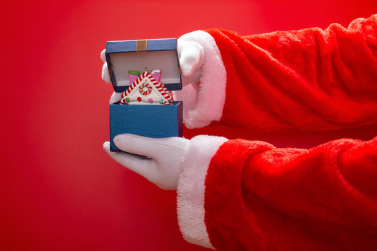 Santa Claus opening a present box with  Christmas house model on red background
