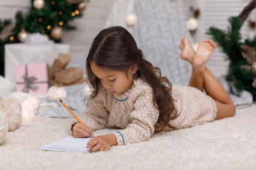 Fototapeta premium Cute child girl writing letter to Santa Claus at home