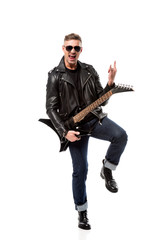 Naklejka premium excited stylish man in leather jacket holding electric guitar and showing rock sign isolated on white