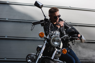 Fototapeta na wymiar classic rider in black sunglasses sitting on motorcycle in garage