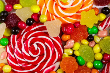 Background of colorful chocolate candies, lollipops, candy cane and jelly sweets