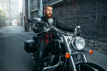 Fototapeta na wymiar Motorcyclist in leather jacket poses on chopper
