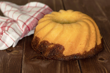 One whole fresh baked marble gugelhupf sweet bread variety with a tea towel on brown wood
