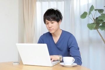 リビングルームでPCを操作する若い男性