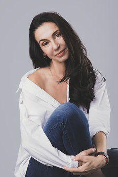 Beautiful Middle Aged Woman Wearing White Shirt And Jeans In Photo Studio