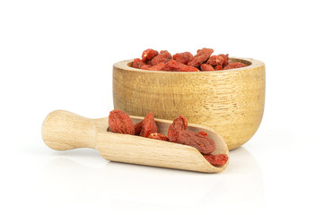 Lot of whole dried red goji berries in a light scoop with wooden bowl isolated on white background