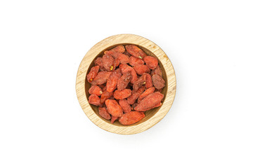 Lot of whole dried red goji berries with wooden bowl flatlay isolated on white background