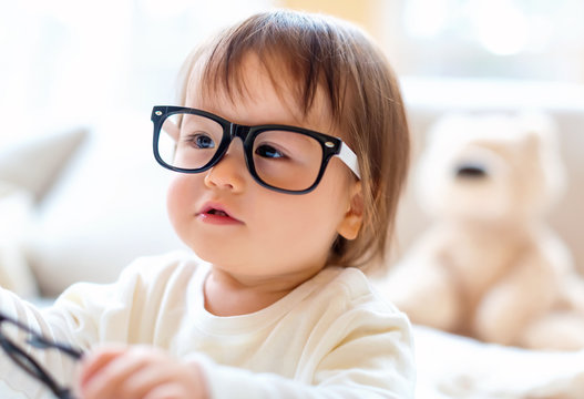 One year old toddler boy with eyeglasses in a living room