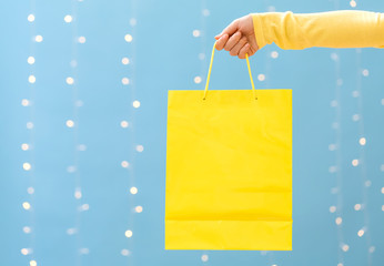 Woman holding a shopping bag on a shiny light blue background