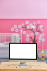 Close up desktop screen, pink baby room interior.