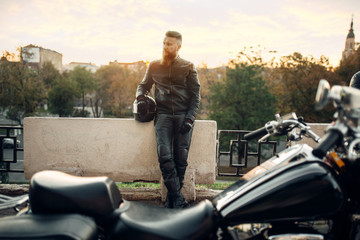 Chopper, biker with helmet in hands on background