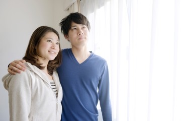 Fototapeta premium 窓辺で寄り添う若いカップル