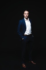 Full length of elegant young handsome man posing in fashionable suit, looking at camera. Studio shot