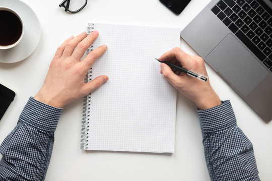 Man writing on notebook in the office. The view from the top.